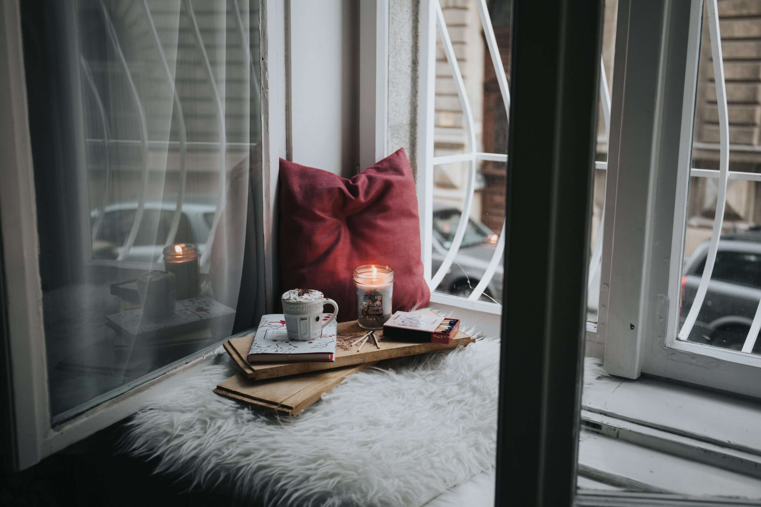 Kaffee, Kerze & Buch auf einem Fensterbrett.