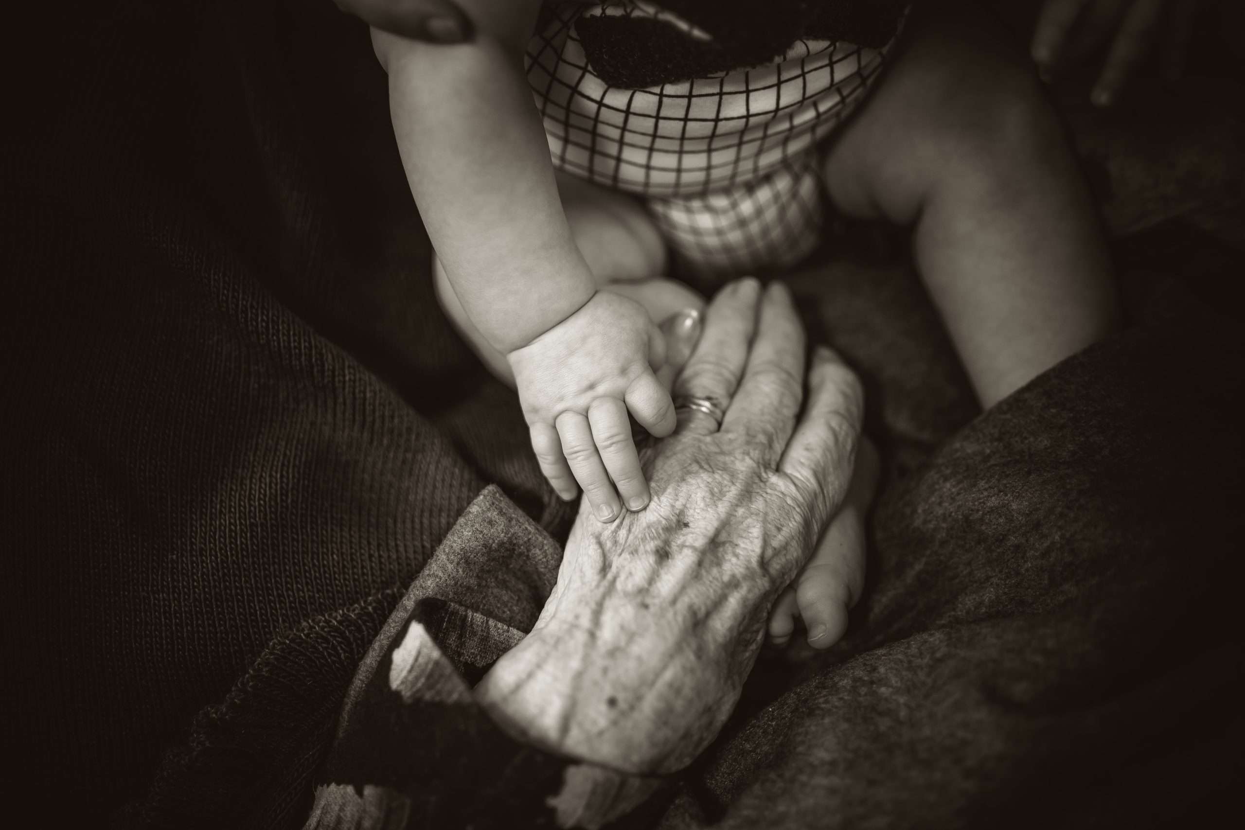 Nahaufnahme von Kinderhänden auf Hand von einer älteren Frau.